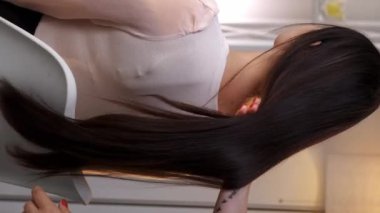 Dikey video. Saç stili tedavisi. Profesyonel salon. Kadın elleri, kaplıcada tedavi gördükten sonra yumuşak, uzun, esmer saçlara dokunuyor..