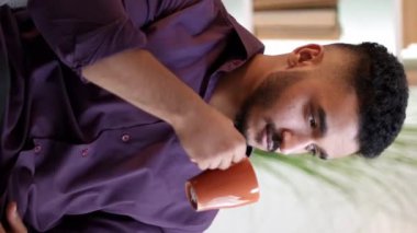 Dikey video. Sabah kahvesi. Ev istirahatı. Haftasonu rahatlama. Düşünceli, düşünceli, hayalperest adam tek başına sıcak bir içecek içiyor..