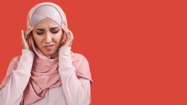 Baş ağrısı. Migren sorunu. Stres basıncı. Hastalıklı, tesettürlü, tesettürlü hasta bir kadın kendini kötü hissediyor kırmızı boş arka planda izole edilmiş tapınaklara masaj yapıyor..