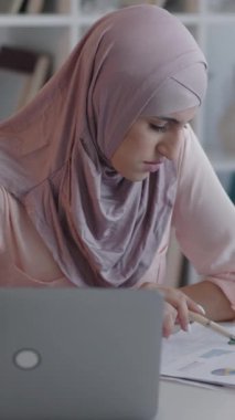 Dikey video. Hesap yöneticisi. Veri kontrolü. İş geliştirme. Kadın çalışan profesyonel pazarlama istatistikleri belgesi ev bilgisayarında..