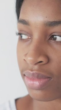 Dikey video. Mutlu ruh hali. Olumlu duygular. Zihinsel refah. Neşeli, kaygısız, iyimser, güler yüzlü, beyaz arka planda yalnız bir kadın..