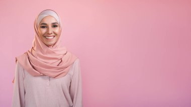 Mutlu kadın. İyimser duygular. Pastel pembe boş bir arkaplanda izole edilmiş başörtüsü takan mutlu, kendine güvenen, gülümseyen kadın yüzü..