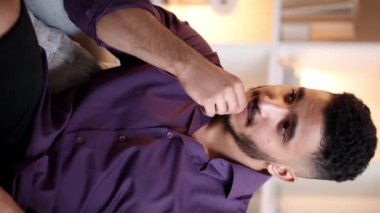 Dikey video. Düşünceli adam. Ev tefekkür. Yalnızlık endişesi. Üzgün, depresif, düşünceli, düşünceli bir adam çenesine dokunmayı düşünüyor..