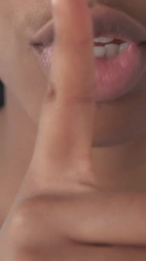 Dikey video. Sessiz ol. Gizli işaret. Sessiz, suskun, parmakları dudaklarında, sessiz komplo sembolü olan bir kadının tanınmaz hale gelmiş portresi..