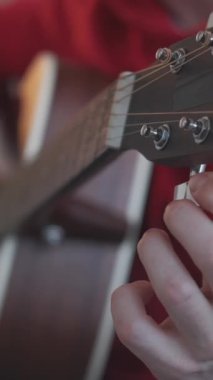 Dikey video. Alet ayarlama. Profesyonel gitarist. Yaratıcı sanatçı parmaklarını kulaklık müzik ekipmanlarının vidalarını ve dişlilerini düzelterek uzattı.