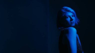 Bunalımlı kadın. Zihinsel sorunlar. Endişeli kadın sosyal kaygısı geriye dönüp bakınca tek renkli neon mavi ışıklar karanlık arka plan boşluğu.