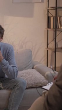 Dikey video. Danışmanlık terapisi. Psikoloji tedavisi. Sağlık hizmetleri danışmanlığı. Psikolog, stres altındaki çivi yiyen adamın ruh sağlığını tartışıyor..