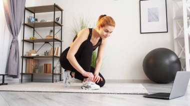 Isınma antrenmanı. Çevrimiçi antrenman. Egzersize hazırım. Spor takımı. Aktif giysili gülümseyen kadın iç dizüstü bilgisayara bakıyor..