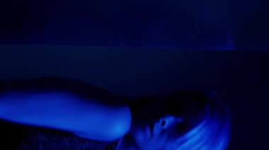 Dikey video. Neon silueti. Bulanık yansıma. Çift pozlama ışık içsel acı kadın acı gizleme zihinsel sorun odak dışı.