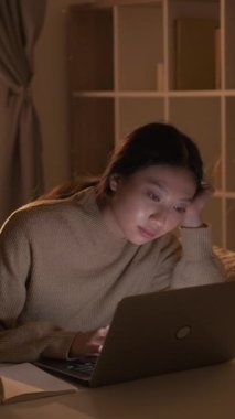 Dikey video. Sıkıcı bir ders. Ev ödevi. Yorgun bir kadın. Yorgun, uykulu bayan, iş yerindeki iç dizüstü bilgisayarını kullanarak dijital ders izliyor..