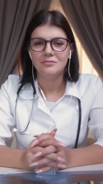 Dikey video. Sanal doktor. Çevrimiçi sağlık hizmeti. Mesafe danışmanlığı. Kadın pratisyen hekim hastane işyerindeki uzaktan toplantıyı dinliyor..