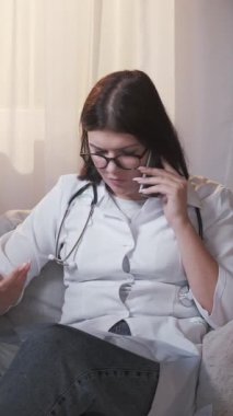 Dikey video. Yaralı teşhisi. Çalışan doktor. Sağlık sigortası. Ciddi bir kadın doktor, hastanede röntgen film danışmanlığı yapan bir hastayı muayene ediyor..