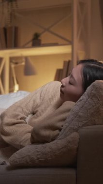 Dikey video. Ev istirahatı. Tatlı rüyalar. Boş zamanlarımızda. Rahat sakin bir kadın sıcak battaniye odasının altında rahat bir kanepede uyuyor..
