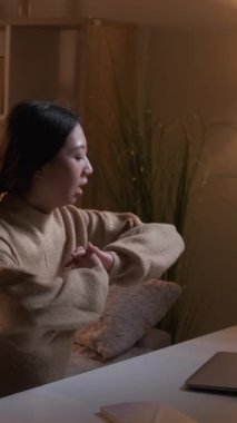 Dikey video. Bağımsız yaşam tarzı. Çalışan kadın. Dijital pazarlama. Diz üstü bilgisayar kullanan hevesli bir kadın. Oturma odasında iç kanepede oturuyor..