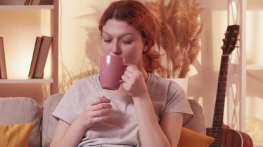 Afiyet olsun. Ev tatili. Sakin bir kadın çay fincanı içiyor kaygısızca dinleniyor tatil havasında rahat koltuklar sıcak pastel renkli mobilyalar..