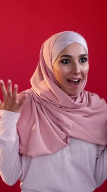 Dikey video. Zafer vay canına. Başarı sevinci. Olumlu tepki. Kırmızı fotokopi arkaplanına izole edilmiş, mutlu, mutlu, mutlu, başörtülü kadın..