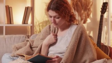 Kitap yaşam tarzı. Ev ödevi. Sakin sakin bir kadın sıcak bir kanepeye sarılmış hafta sonu tatili eğlenceli eğlenceli bir hikaye rahat bir eğlence.