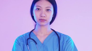 Acil servis hemşiresi. Ambulans servisi. Ciddi sorumluluk sahibi kadın doktor çapraz kollar mavi üniformalı açık pembe arka plan..