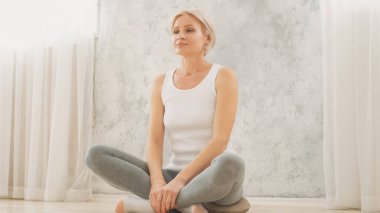 Yoga yapıyorum. Barışçıl bir uygulama. Sakin, uyumlu, dengeli bir kadın. Nilüfer pozisyonunda, yerde oturuyor. Hafifçe nefes alıyor..