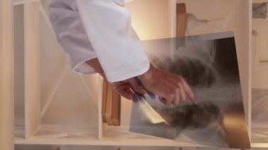 Dikey video. Teşhis konsültasyonu. Çevrimiçi doktor. Akciğer hastalığının röntgenini açıklayan zeki bir tıp uzmanı hastanenin iç kısımlarında oturuyor..