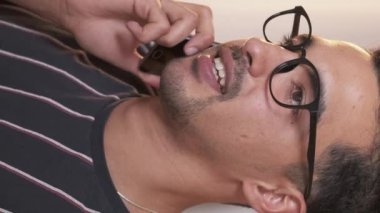 Dikey video. Cep telefonu. Telefon görüşmesi. Akıllı telefondan konuşan gülümseyen adam cep telefonuyla iletişim kuruyor..
