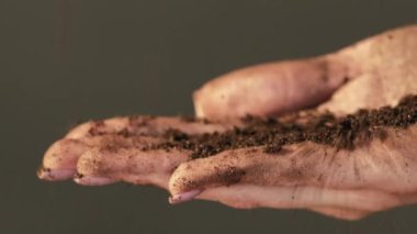 Gübre testi. Toprak kontrolü. Yer analizi. Koyu renk fotokopi arkaplanındaki verimli toprakları incelemek için kadın eli dökülüyor.