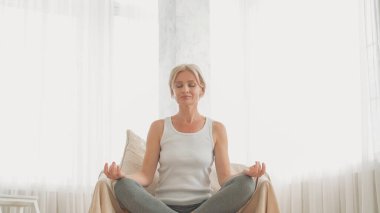 Meditasyon refahı. Aile içi şiddet. Yoga nilüfer pozisyonunda oturan sakin kadın koltukta oturup Mudra 'daki nefes alan ellere odaklandı..