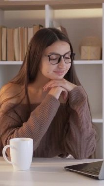 Dikey video. Çevrimiçi film. Cihaz eğlencesi. Ev tatili. Mutlu, gülümseyen bir kadın dizüstü bilgisayarda oturmuş açık bir şekilde internet şovu izliyor..
