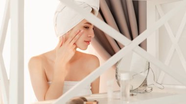 Sabah rutini. Deri besler. Yüz masajı. Kozmetik tedavi. Genç ve güzel bir kadın tuvalet masasında elmacık kemiğine dokunuyor..