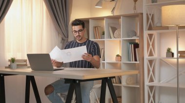Çevrimiçi rapor. Video konferansı. Uzaktan kumanda. İş belgelerine sahip uzman adam internet sunumunda konuşuyor. Ev ofisinin fotokopi masasında dizüstü bilgisayarında..