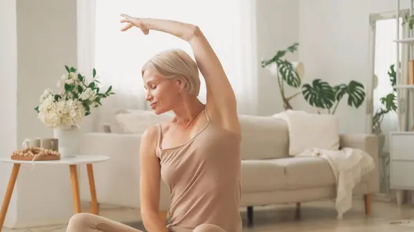 stock image Pilates workout. Stretching exercise. Healthy morning. Fit happy woman in comfortable activewear practicing side bend indoors in living room at home.