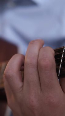 Dikey video. Müzik ilhamı. Profesyonel besteci. Akustik ses. Yaratıcı hünerli erkek elleri gitar enstrümanında favori şarkıyı söylüyor..