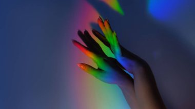 Gökkuşağı elleri. Prizma ışığı. Çeşitlilik ahengi. LGBT hakları. Simgesel poziyondaki kadın kolları fotokopi uzayının mavi gölgesi arkaplanında parlak neon rengi gradyanı..