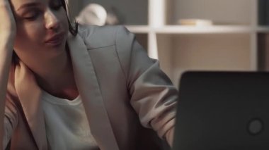 Uykucu işçi. Aşırı çalışma yorgunluğu. Sağlıksız iş yükü. Uzun çalışma saatlerinden sonra bilgisayarını kapatmaktan yorgun bir kadın karanlık çalışma alanında geç saatlere kadar çalışıyor..