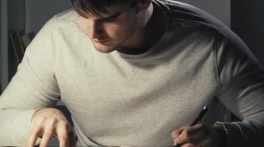 Test hazırlığı. Gece son teslim tarihi. Evde eğitim. Çalışkan erkek öğrenci kitap yazıyor karanlık kampüste geç saatlere kadar öğreniyor..