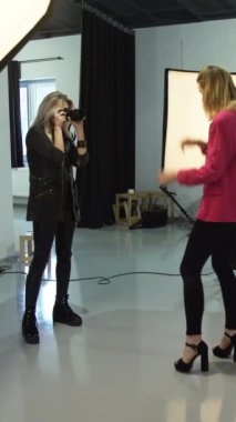 Dikey video. Kuliste moda. Kıyafet fotoğrafçılığı. Kadın fotoğrafçı profesyonel ekipman kullanıyor. Fotoğraf çekiyor. Güzel bir model..