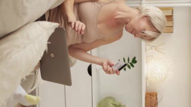 Dikey video. Çevrimiçi bankacılık. İnternet alışverişi. Sanal alım. Kredi kartı alışverişi yapan bir kadın dizüstü bilgisayarla ev içi koltukta oturuyor..