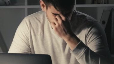 Fazla mesai. Son teslim tarihi stresi. İş yorgunluğu. Uykucu, yorgun, serbest çalışan, dizüstü bilgisayarda yazan, işini bitiren, gözlerini ovuşturan, karanlık ofis odasında uyuyan bir erkek..