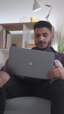 Dikey video. Ev telgrafı. Web görüşmesi. Sanal müzakere. Kendine güvenen ciddi bir iş adamı modern iç mekandaki koltukta dizüstü bilgisayar kullanarak projeyi tartışıyor..
