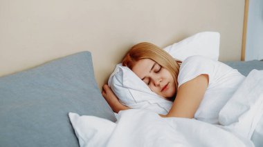 Yatak rahatla. Güzel bir rüya. Rahat bir sabah. Sakin, tembel kız uyuyor. Yastığa sarılıyor. Rahat yatak odasında dinleniyor..
