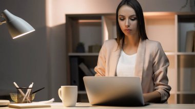 Konsantre işçi. Uzaktan kumanda. Bilgisayarda yazı yazan düşünceli, düşünceli genç bir kadın. Konforlu iş yerinde online bilgi arama işini bitiriyor..