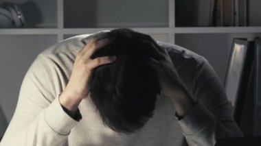Proje başarısız. İşyeri harabesi. Kariyer krizi. Gece ağrısı. Sinirli, hoşnutsuz, baş ağrısı çeken bir erkek çalışanın karanlık ofis odasında endişe etmesi..