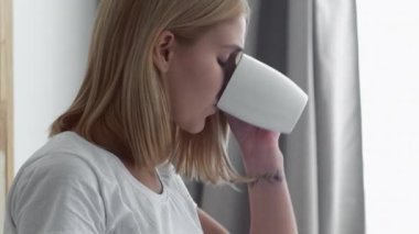 Medya sabahı. Mobil rutin. Modern hayat. Odaklanmış, kendine güvenen, çay içen, internette gezinen ışık odasında arayan bir kadın..