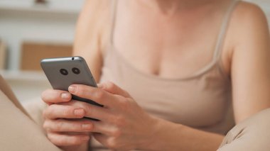 Online mesaj. SMS iletişimi. Mobil teknoloji. Elinde akıllı telefonuyla evde internet üzerinden sanal sohbet mesajları atan tanınmayan bir kadın..