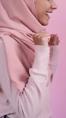 Dikey video. Heyecanlı bir ifade. İyi şanslar. Mutlu tesettürlü kadın profili. Pembe üzerine izole edilmiş başparmak gösterme başarısını kutluyor..