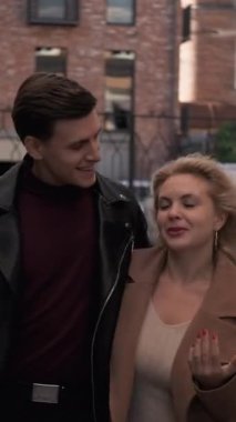 Dikey video. Şehir tarihi. Romantik yürüyüş. Sonbahar şehir gezisi. Mutlu, güler yüzlü bir çift. Sohbetin tadını çıkarıyorlar. Sarılıyorlar..