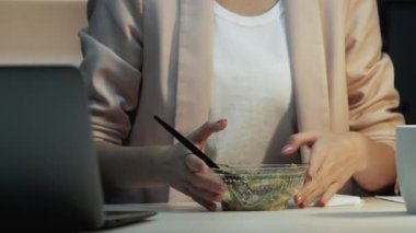 Yemek molası. Kötü bir iş yeri. Yoğun ofis programı. Hüzünlü aç kadın çalışan, yasaklı yiyecek saklayan sağlıksız iş koşullarında dizüstü bilgisayar yazan..