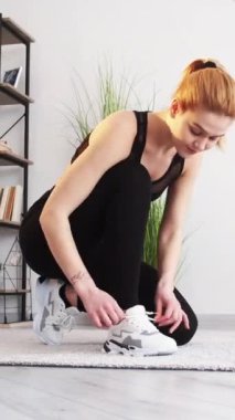 Dikey video. Kardiyo çalışması. Evde fitness. Sabah koşusu. Sağlıklı bir yaşam tarzı. Aktif giyimli atletik kadın halının üzerinde koşuyor..