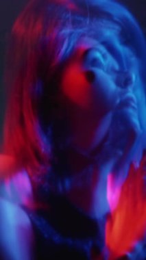 Dikey video. Bipolar bozukluk. Dikkati dağılmış bir kadın. Neon kırmızı mavi siluet hüzünlü ruh hali değişken kızgın kötü kahkaha iki kat bulanık odaklanma.