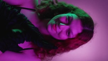 Dikey video. Kötü kadın. Kurnaz gülümseme. Güzel, büyüleyici kadın entrikaları. Siyah eldivenler. Akşam elbisesi..